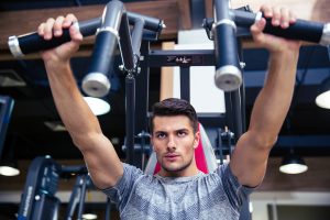 Portrait of a fitness man doing exercise on fitness machine in gym